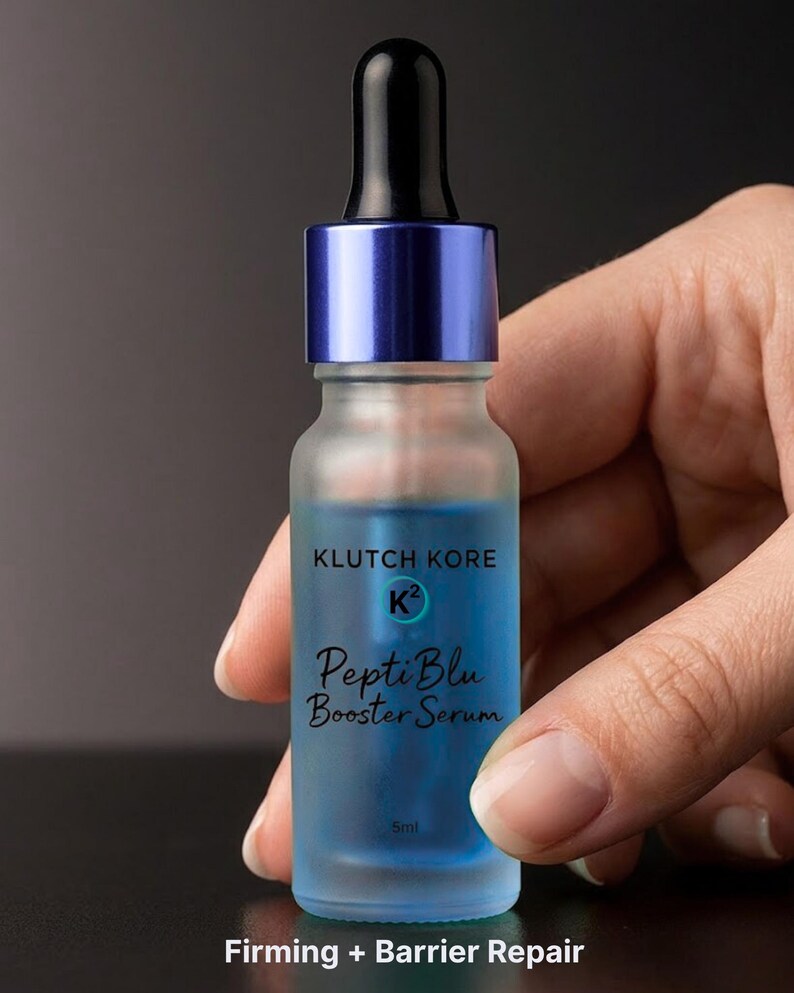 May include: A frosted glass bottle of PeptiBlu Booster Serum with a blue liquid inside. The bottle has a blue cap and a black dropper. The text "KLUTCH KORE" and "PeptiBlu Booster Serum" are printed on the bottle. The bottom of the bottle reads "Firming + Barrier Repair".