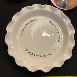 May include: A set of three ceramic mugs with a speckled, matte finish. The mugs are in shades of cream, light gray, and dark gray. Each mug has a simple, minimalist design and a rounded handle.