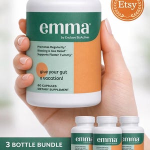 Pode incluir: Frasco branco de suplemento alimentar "emma" com rótulo verde e laranja, segurado na mão. O texto inclui "Promove a regularidade, alivia o inchaço e gases, apoia uma barriga mais lisa". Frascos e cápsulas adicionais são visíveis. "Dê férias ao seu intestino!" também está escrito.
