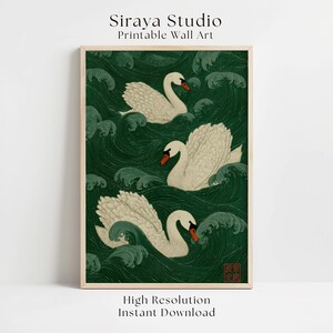 Op de afbeelding: Ingelijste printbare wandkunst met drie witte zwanen met oranje snavels, zwemmend in een donkergroene zee met gestileerde golven. Het kunstwerk bevat de tekst "Siraya Studio Printable Wall Art" en "High Resolution Instant Download".