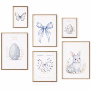Könnte beinhalten: Eine Sammlung gerahmter Aquarelldrucke mit Ostern- und Frühlingsmotiven. Die Drucke zeigen einen Schmetterling, eine blaue Schleife, ein Osterei, ein Kaninchen und die Worte "Happy Easter" und "Butterfly Garden". Die Rahmen sind hellbraun.