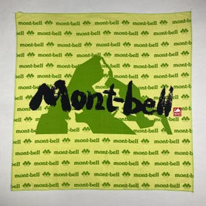 Könnte beinhalten: Ein quadratisches, hellgrünes Bandana mit dem Text "Mont-bell" in großen, schwarzen Buchstaben im Pinselstil. Das Design umfasst eine grüne Berg-Grafik und den wiederholten Text "mont-bell" in kleinerer Schrift.