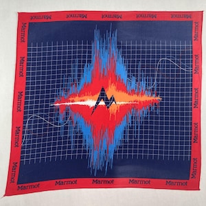 Puede incluir: Pañuelo cuadrado azul marino con un borde rojo con el nombre de la marca "Marmot". El diseño central muestra un gráfico abstracto vibrante en rojo, naranja y azul, que se asemeja a una onda de sonido. Un logotipo de montaña blanco está en el centro.