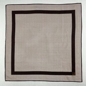 Könnte beinhalten: Ein quadratisches, beiges Taschentuch mit dunkelbraunem Rand und gepunktetem Muster. Das Taschentuch hat einen dunkelbraunen quadratischen Rand und ein kleines Logo in der Ecke. Das Gesamtdesign ist schlicht und elegant.