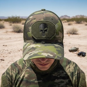 Può includere: Cappellino da baseball mimetico con toppa a teschio nero. Il cappellino ha un retro in rete e una visiera curva. Il cappello è realizzato in un tessuto resistente ed è progettato per l'uso all'aperto. La toppa a teschio è centrata.