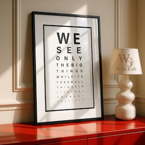 Könnte beinhalten: Ein gerahmter Wandkunstdruck mit einem schwarz-weißen Sehtest-Design und dem Text: WE SEE ONLY THE BIG THINGS WHILE ITS THE SMALL THINGS IN LIFE THAT ARE MOST PRECIOUS. Der Druck befindet sich in einem schlichten schwarzen Rahmen mit weißem Passepartout.