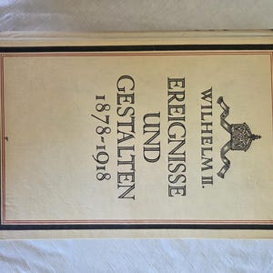May include: A hardcover book with a cream-colored cover featuring black text that reads Wilhelm II. Ereignisse und Gestalten 1878-1918. The cover includes a black and red rectangular border and a small black graphic of a crown with ribbons.