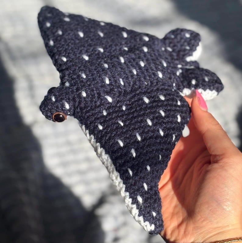 K&ouml;nnte beinhalten: Geh&auml;keltes Walhai-Pl&uuml;schtier in Marineblau mit wei&szlig;en Punkten. Das Kuscheltier hat einen wei&szlig;en Rand und ein braunes Auge. Dieses handgefertigte Spielzeug ist ein Unikat.
