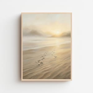 Può includere: Una stampa incorniciata di una scena di spiaggia con impronte nella sabbia che conducono all'oceano. L'opera d'arte presenta una calda tavolozza di colori beige, giallo e marrone chiaro, con un'atmosfera morbida e nebbiosa e un'alba o un tramonto sullo sfondo.