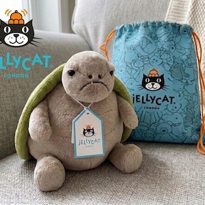 Op de afbeelding: Een witte keramische mok met een zwart handvat en de tekst "But First, Coffee" in handschriftstijl. De mok staat op een wit oppervlak. De mok is 10 cm hoog.