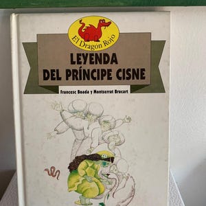 May include: A vintage book titled "Leyenda Del Príncipe Cisne" with a red dragon illustration. The cover features a drawing of figures in yellow and white clothing, and a swan. The author's names are also visible.