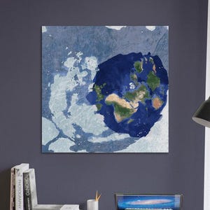 Puede incluir: Una impresión en lienzo cuadrada que presenta un mapa del mundo estilizado. Los continentes se representan en tonos verdes y marrones, rodeados por un océano azul oscuro y un fondo azul claro texturizado. La obra está montada en una pared azul oscuro.