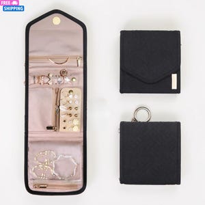 Peut inclure: Un organisateur de bijoux noir avec plusieurs compartiments, dont un design enroulable et deux étuis carrés plus petits. L'organisateur est ouvert, affichant divers colliers, boucles d'oreilles et bracelets. Les étuis sont fermés, l'un avec un accent doré.