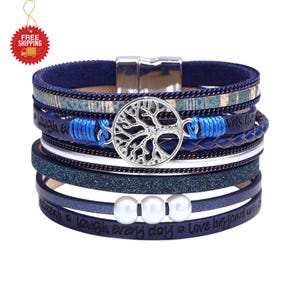 May include: A multi-layered blue bracelet with a silver tree of life charm and three white pearls. The bracelet has a magnetic clasp and features the words "laugh every day" and "love beyond words".