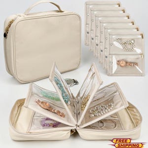 Puede incluir: Organizador de joyas beige con múltiples bolsas transparentes con cremallera y compartimentos. El organizador está abierto, mostrando varios brazaletes, collares y relojes. También es visible un estuche de transporte beige a juego con asa.