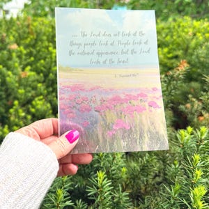 May include: A greeting card with a floral field design in shades of pink, purple, and green. The card features a quote from 1 Samuel 16:7: "...The Lord does not look at the things people look at. People look at the outward appearance but the Lord looks at the heart."