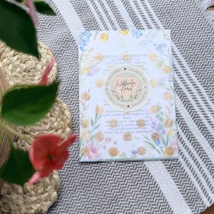 May include: A rectangular prayer card featuring a watercolor floral border in shades of blue, yellow, and pink. A circular sticker in the center displays the text Watercolor Floral and The Grace Habit with a heart icon and gold foil accents.