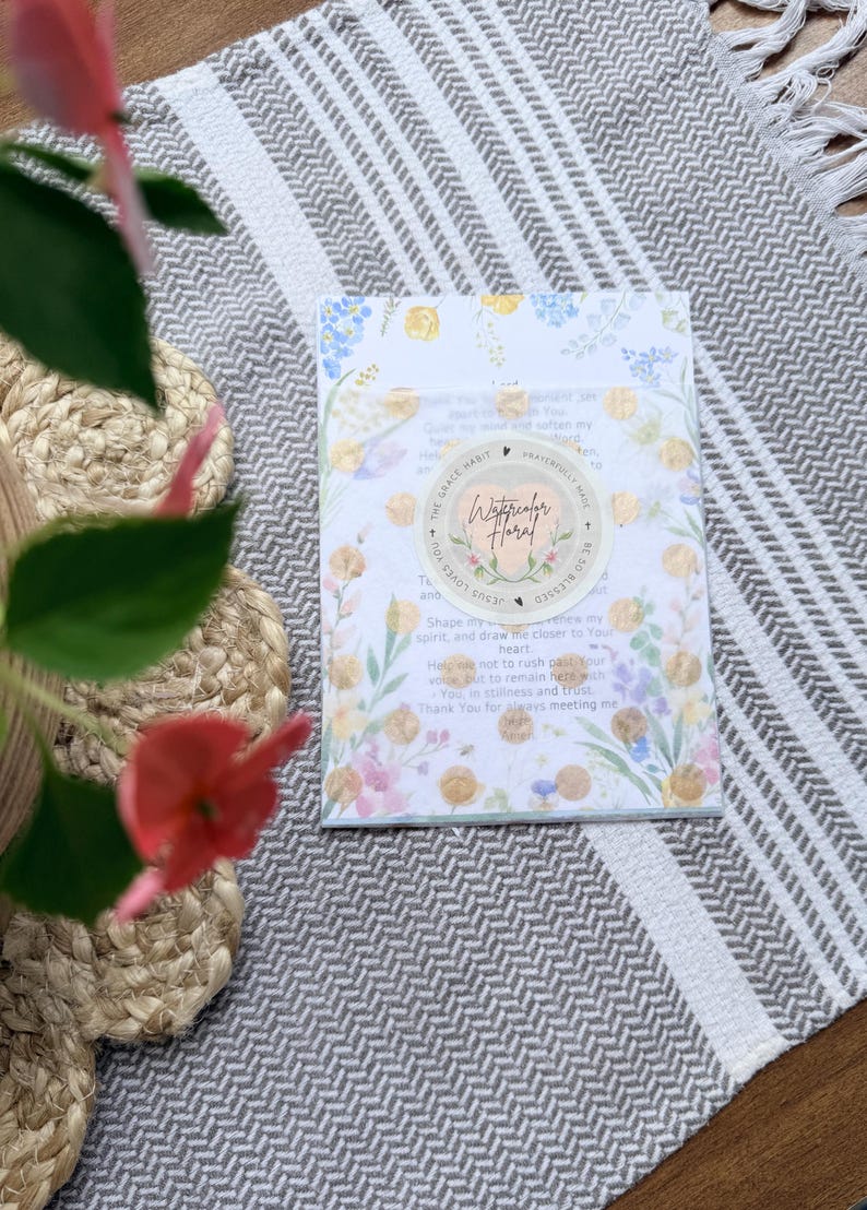 May include: A rectangular prayer card featuring a watercolor floral border in shades of blue, yellow, and pink. A circular sticker in the center displays the text Watercolor Floral and The Grace Habit with a heart icon and gold foil accents.