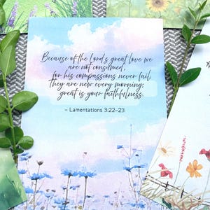 May include: A rectangular card featuring a watercolor sky background with blue and white clouds above a field of blue flowers. The text reads: Because of the Lord's great love we are not consumed, for his compassions never fail. They are new every morning, great is your faithfulness. - Lamentations 3:22-23.