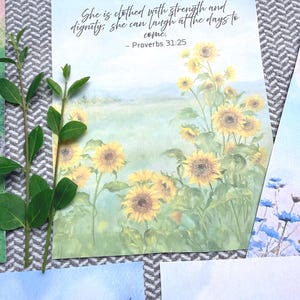 May include: A rectangular print featuring a watercolor painting of a field of yellow sunflowers under a soft blue sky. The text reads: She is clothed with strength and dignity; she can laugh at the days to come. - Proverbs 31:25.