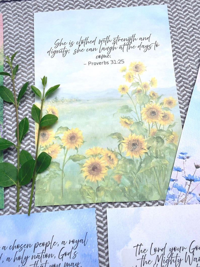 May include: A rectangular print featuring a watercolor painting of a field of yellow sunflowers under a soft blue sky. The text reads: She is clothed with strength and dignity; she can laugh at the days to come. - Proverbs 31:25.