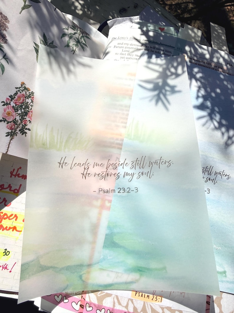 May include: Watercolor-style art print with the text "He leads me beside still waters. He restores my soul." from Psalm 23:2-3. The print features a soft, blurred landscape with green and blue hues, evoking a sense of peace.
