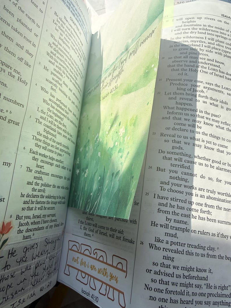 May include: An open Bible with thin pages featuring printed text in columns. A green watercolor bookmark with the text "They that wait upon the Lord shall renew their strength" and "Isaiah 40:31" is inserted. A stamp reads "not for i am with you" and "Isaiah 41:10".