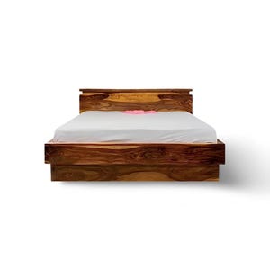 May include: A wooden bed frame with a headboard and a low-profile footboard. The bed frame is made of dark brown wood with a natural grain pattern. The bed is covered with a white sheet and a pink decorative item.
