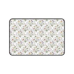 May include: A rectangular desk mat featuring a repeating pattern of Venus flytrap plants in shades of green, yellow, and purple on a white background. The design includes small sprigs of foliage and tiny flowers interspersed between the plants.