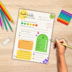 Puede incluir: Una hoja de trabajo de "Daily Reflection" con una ilustración de sol y el texto "Daily Reflection". La hoja de trabajo incluye secciones para sentimientos, actividades y metas futuras. También se ve un juguete pop-it colorido y lápices.