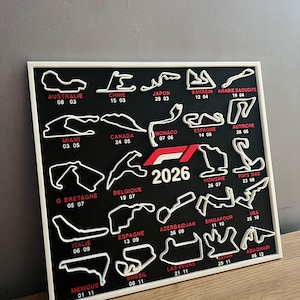 May include: A black and white framed wall art piece featuring Formula 1 race track layouts for the 2026 season. Each track is labeled with its name and race date. The frame is white.