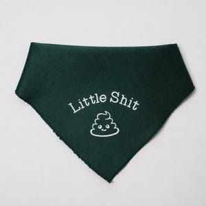 May include: Dark green dog bandana with the text "Little Shit" in white, along with a smiling poop emoji. The bandana is triangular in shape and has a frayed edge.