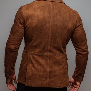 May include: A brown suede blazer with a classic two-button closure and notched lapels. The jacket features two front pockets and buttoned cuffs. The back view showcases the tailored fit and rich color of the garment.