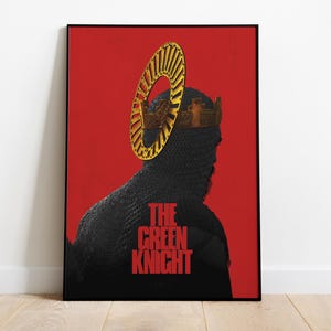 May include: Framed art print featuring a silhouette of a knight in chainmail, wearing a crown and a halo-like structure, set against a red background. The text "THE GREEN KNIGHT" is displayed in red. The artwork is in a black frame.
