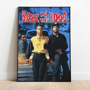 May include: A framed poster featuring the movie title "Boyz n the Hood" in red and white lettering. The image shows three men posing in front of a car. One man wears a yellow and black shirt, and another wears a black cap.