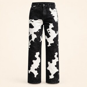 May include: High-waisted denim jeans featuring a black and white cow print pattern. These straight-leg pants include a button and zipper fly closure, belt loops, and two front pockets, showcasing a bold, contrasting animal-inspired design.