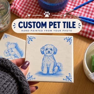 May include: A square ceramic tile featuring a hand-painted blue illustration of a fluffy dog sitting in the center. The tile has decorative blue scrollwork in each corner. The text CUSTOM PET TILE HAND-PAINTED FROM YOUR PHOTO is visible.