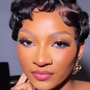 Puede incluir: Retrato en primer plano de una persona con cabello oscuro y ondulado peinado con ondas de dedo. La persona tiene labios carnosos, maquillaje de ojos dramático y aretes dorados. La piel tiene una tez cálida y brillante.