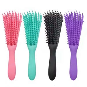May include: Four colorful hair detangling brushes. The brushes are in shades of pink, teal, black, and purple. Each brush has a handle and a head with flexible bristles designed for detangling hair.