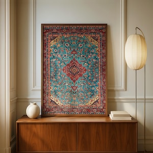 May include: A framed rug with an elaborate design. The rug has a central red and black medallion, set against a teal background with floral motifs. The border is red with detailed patterns. The frame is dark brown. The rug is a decorative home item.
