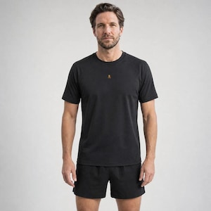 Könnte beinhalten: Ein schwarzes kurzärmeliges T-Shirt mit Rundhalsausschnitt und einem kleinen orangefarbenen Buchstaben B als Logo mittig auf der Brust, kombiniert mit passenden schwarzen Sportshorts. Das Set ist einfarbig und schlicht geschnitten.