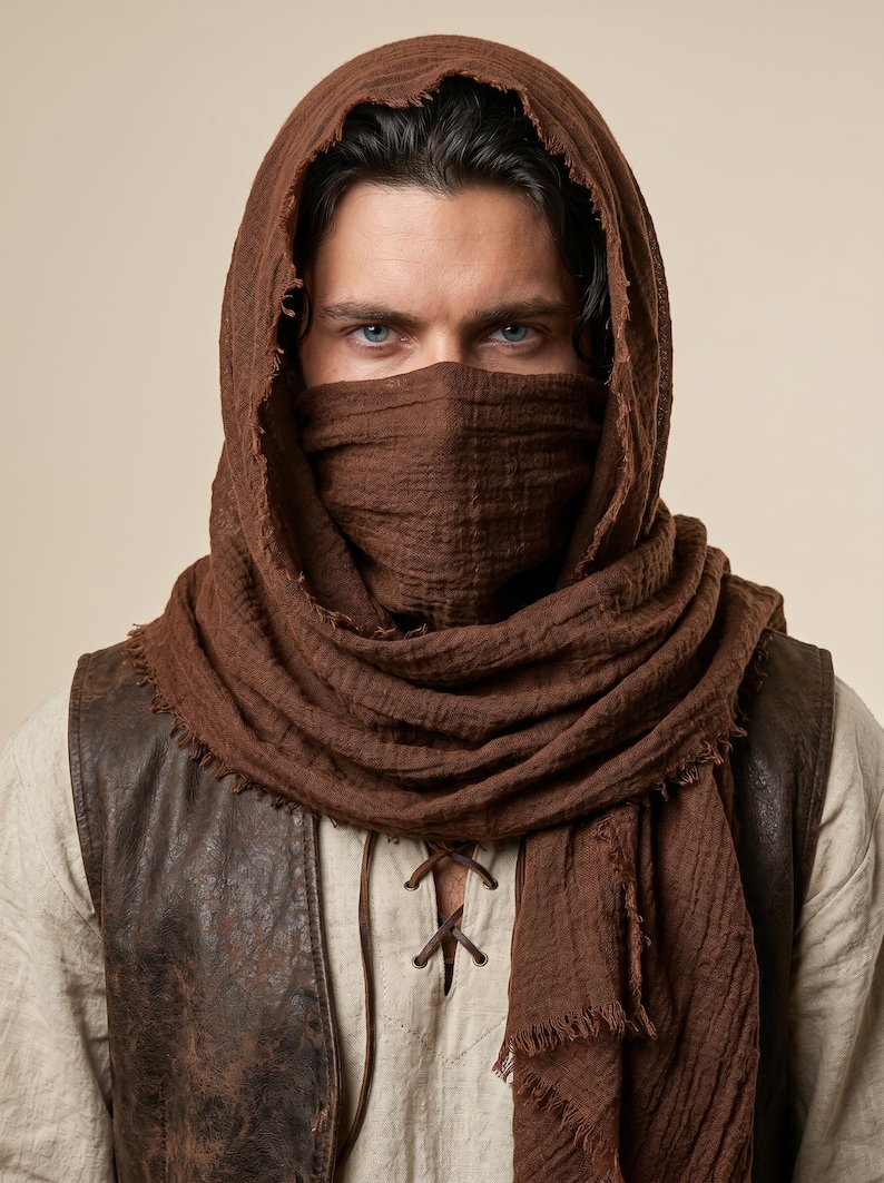 May include: A dark brown textured fabric hood and face covering scarf with frayed edges. The scarf is draped over the head and wrapped around the lower face, featuring a lightweight, crinkled material that provides full coverage.