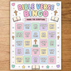 May include: A Bible Verse Bingo game card featuring a pastel color palette. The header reads BIBLE VERSE BINGO and MARK THE SCRIPTURE. The grid contains various book and verse references, with a central free space marked with a cross icon.