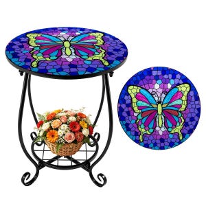 May include: A round mosaic side table with a butterfly design in shades of blue, purple, green, and yellow. The table has a black metal frame and a lower shelf with a basket of flowers. A matching mosaic butterfly is shown separately.