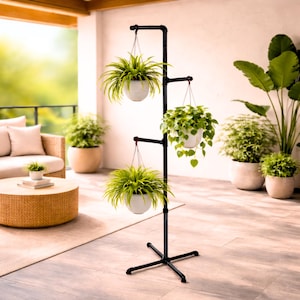 May include: A black metal plant stand with three tiers, each holding a white hanging planter filled with green plants. The stand is on a patio with other potted plants and outdoor furniture.