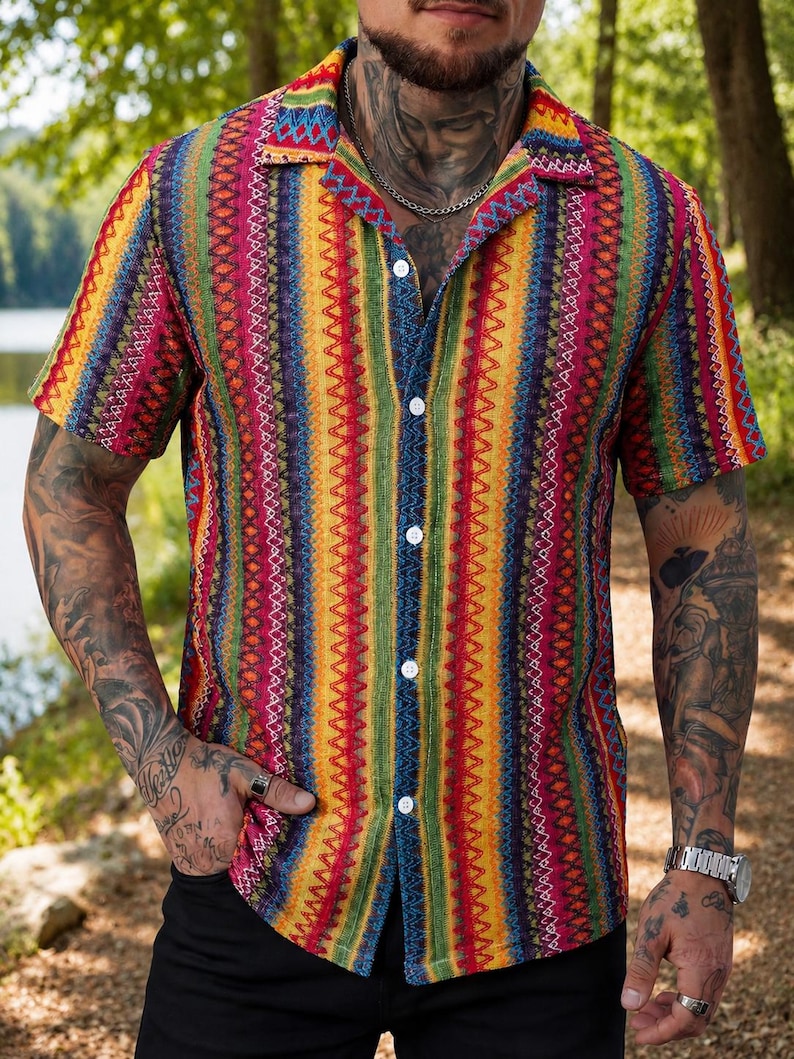 May include: A short-sleeve button-down shirt featuring a vibrant, multi-colored vertical striped pattern. The design incorporates repeating geometric zig-zag lines in shades of red, yellow, green, and blue, finished with a classic collar.