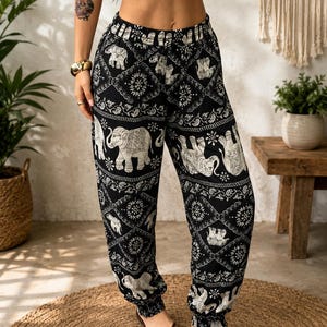 May include: Black and white patterned trousers featuring a repeating elephant motif and intricate geometric designs. These loose-fitting trousers have an elasticated waistband and gathered elastic cuffs at the ankles, providing a relaxed silhouette.
