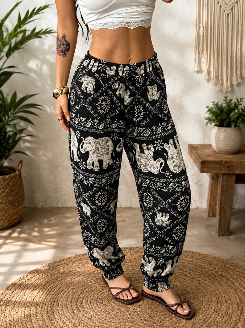 May include: Black and white patterned trousers featuring a repeating elephant motif and intricate geometric designs. These loose-fitting trousers have an elasticated waistband and gathered elastic cuffs at the ankles, providing a relaxed silhouette.