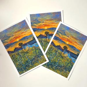May include: Three art prints depicting a sunset over a mountain range. The artwork uses an impressionistic style with vibrant orange, yellow, blue, and green hues. Each print is framed with a white border, creating a striking visual.