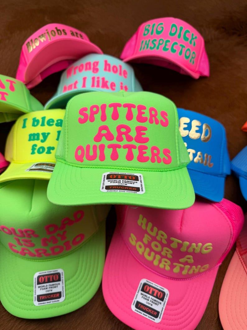 May include: A collection of trucker hats in various neon colors, including pink, green, and blue. Each hat features bold, humorous text in contrasting colors. The hats have a mesh back and a foam front.
